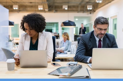 stock woman and man sat next to each other at wooden desk